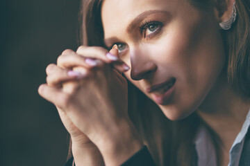 Obraz premium Close up studio Portrait of Beautiful thoughtful young woman with long hair against dark background.
