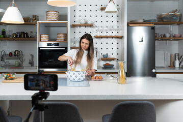 Young vlogger woman vlogging about cooking at her apartment domestic kitchen cook and making video...