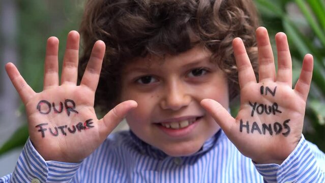 Europe, Italy - 7 year old boy child  environmentalist with written on his hands our future is in your hands - environmentalist protest against cmilmatic changes and global warming - youth for future