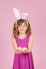 Smiling little girl with bunny hairband and easter eggs in hands. Vertical orientation