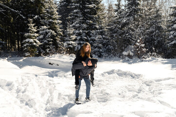 young couple fooling around while on a winter walk near the forest. a general plan of a couple in love against the backdrop of winter nature.