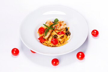Special shrimp pasta dish made by restaurant chef with tomatoes and olives shot on white background