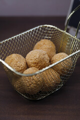 croquetas en forma de bola rebozadas y preparadas para freír en cesta de freidura