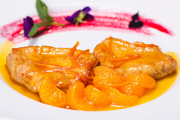 Special dish prepared by a restaurant chef. Composition with tangerines, pork chop and flowers