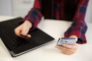 Young girl buying online with credit card and mobile phone. Woman making money transfer with smartphone app and debit bank card. Female purchasing in internet store with new cellphone gadget