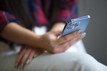 Woman using modern smartphone. Young female browsing internet news feed on new mobile phone. Person communicating online with cellphone device