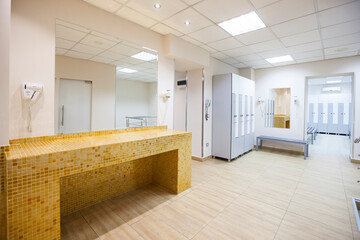 wide frame with a white locker room with wooden cabinets and benches