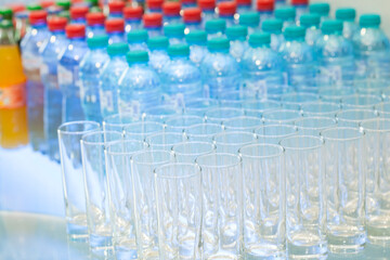 Set of empty glasses on table indoors near a lot of drinks of different types