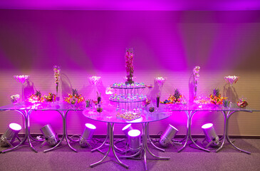 Candy bar, table with sweets, delicious sweet cupcakes lie on a glass plate on a table with lights