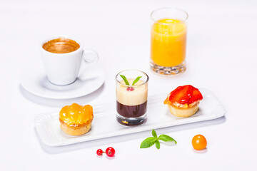 beautifully colored cakes on plate and decoration on white background with coffee and orange juice

