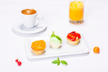 beautifully colored cakes on plate and decoration on white background whith coffe and orange juice