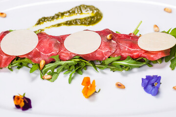 Special plate made by the chef with tabs on a bed of herbs and decorations on a white background