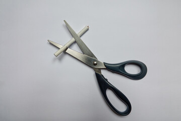 Cigarette in scissors on white background. Bad habit. Quit smoking as a New Year's resolution. High...