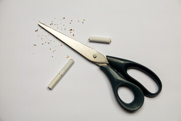 Cigarette in scissors on white background. Bad habit. Quit smoking as a New Year's resolution. High...