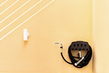Black Water Pipe for Gardening Hanging on Faucet Against Wall. cleaning tool, garden and utility in...