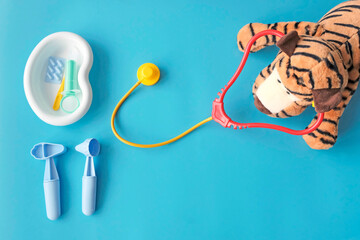 Children's first aid kit medical. Instruments. Tiger cub toy with a phonendoscope. Blue background. Copyspace.