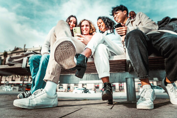 Multicultural group of friends using smart mobile phone - Students sitting in a bench typing on...