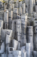 Basalt rock pillars columns at Reynisfjara beach near Vik, South Iceland. Unique geological volcanic formations. Natural stone texture background.