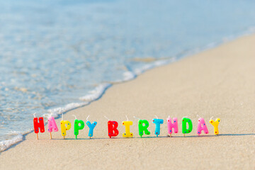 Happy birthday colorful candles on a beach