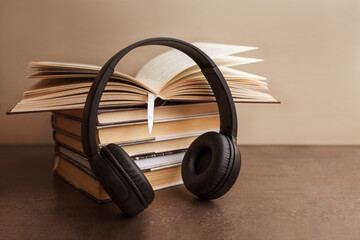 Audio book concept. Headphones on books on brown background. Copy space