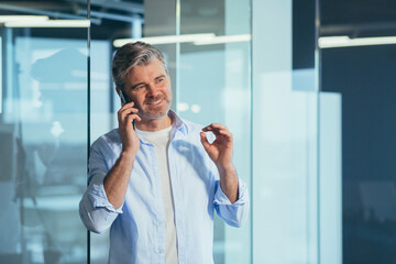 Senior and experienced successful gray-haired man talking on the phone, working in a modern office businessman