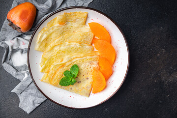 sweet thin pancake persimmon fruit crepe Shrovetide holiday Maslenitsa dessert breakfast pancakes food snack on the table copy space food background 