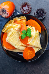 sweet thin pancake persimmon fruit crepe Shrovetide holiday Maslenitsa dessert breakfast pancakes food snack on the table copy space food background 