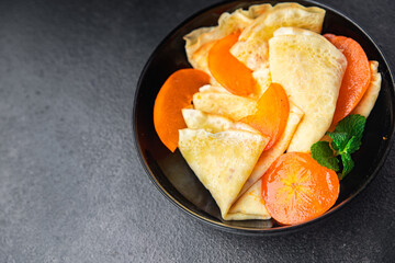 sweet thin pancake persimmon fruit crepe Shrovetide holiday Maslenitsa dessert breakfast pancakes food snack on the table copy space food background 