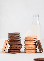 Fototapeta na wymiar Many chocolate and milk sandwich cookies with cream filling and milk bootle on a white table.