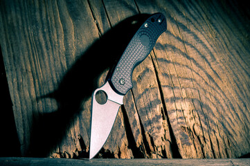 Knife with a hole in the blade. A knife and a hard shadow from it. Knife on a textured wood...