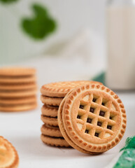 Sweet sandwich cookies with chocolate cream and milk bootle on a white table. Sandwich cookies close up.