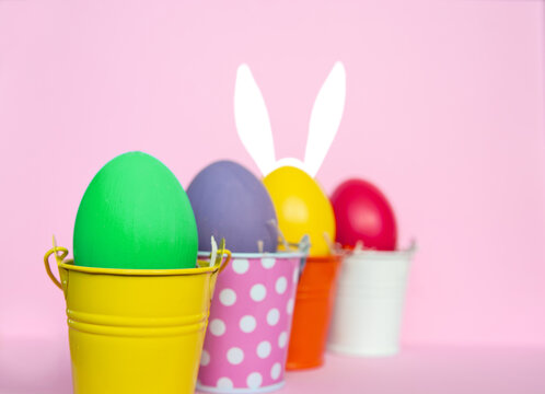 Easter eggs with bunny Rabbit ears in colored buckets, selective focus image, Card Happy Easter	