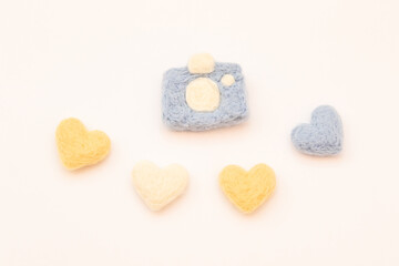 Four hearts and a felted camera on a white background. Felted toys. Handmade requisites