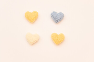 Four felted hearts of different colors on a white background. Felted toys. Handmade requisites