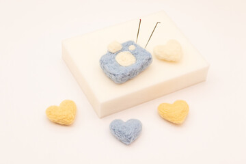 Four hearts and a wool camera on white background. Felted toys. Felting mat and needles. Handmade requisites