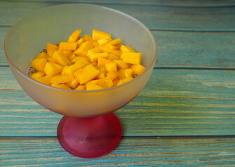 chia pudding with coconut milk and mango in a pink glass glass stands on a blue wooden table. side view.  gluten-free, lactose-free. vegan dessert