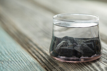 shungite stones on a wooden  background used in alternative medicine for water purification and...