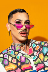 Portrait of a young drag queen in colorful dress on yellow background
