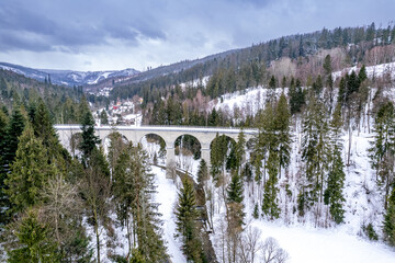Wiadukt kolejowy w górach zimą nad rzeką i drogą. Wisła, Beskid Śląski w Polsce - obrazy, fototapety, plakaty