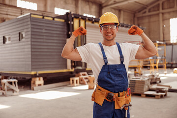 Cheerful male worker demonstrating his strong muscular arms