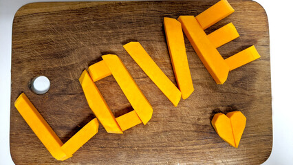 Juicy inscription love and heart on a wooden board of orange pumpkin for valentine's day