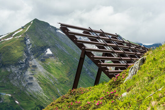 Avalanche protection fences in the alpine mountains. Steel snow bridges and sliding snow stands. Summer mountain landscape.