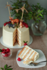 White, layered, multi-layer cake from biscuit smeared with cream, round shape, white cream inside, a piece is cut, a piece of cake with a fork, a cut of the cake, food, sweets