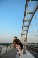 Young woman riding her longboard on the bridge