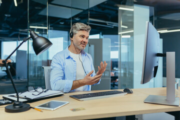 Senior and experienced employee, advises the buyer on a video call, the man works in a modern...