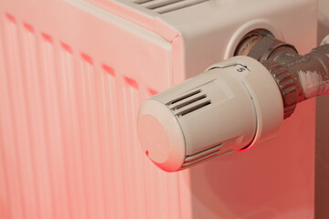 Heating radiator and temperature knob. The temperature is at the highest level of 5. Warmth concept with red color tones.
