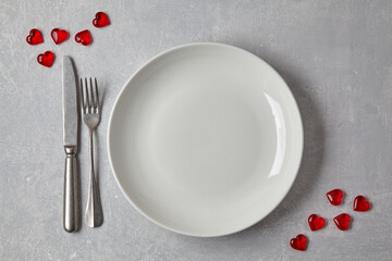 Empty white plate with cutlery and red caramel hearts