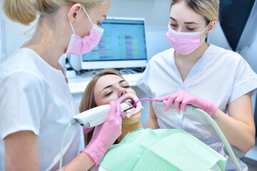 Woman dentist and assistant scaning patient's teeth with  3d scanner.