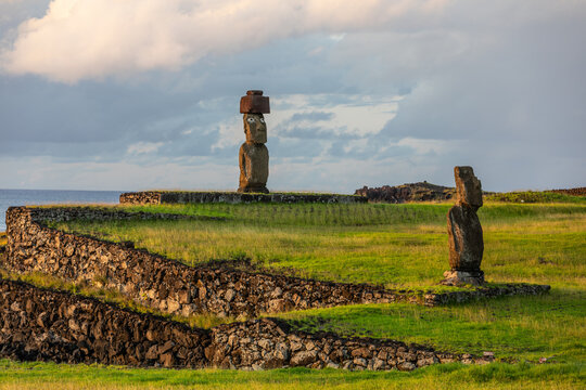 Zwei Moais in Ahu Tahai mit Korallenaugen und einem roten Hut, den Pukau, an der Küste von Hanga Roa auf Rapa Nui