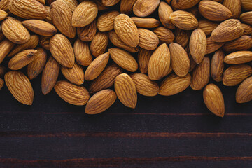 Close up almonds on dark wooden table. Organic health protein vegetarian food. Background copy space